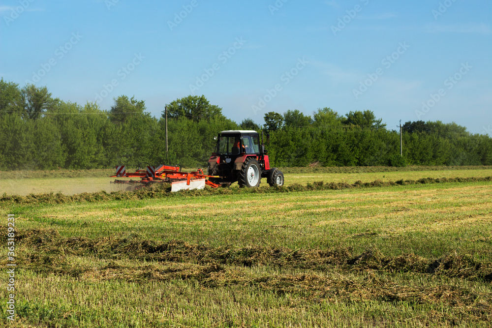 Tractor working at field Haymaking in the countryside Beautiful scenery and blue sky. Tractor working at field Haymaking in the countryside Beautiful scenery and blue sky.