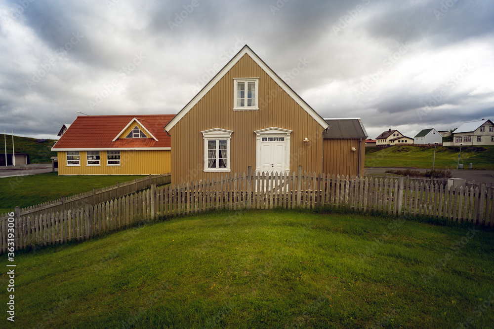 Typical nice Icelandic house with dramatic clouds and green grass