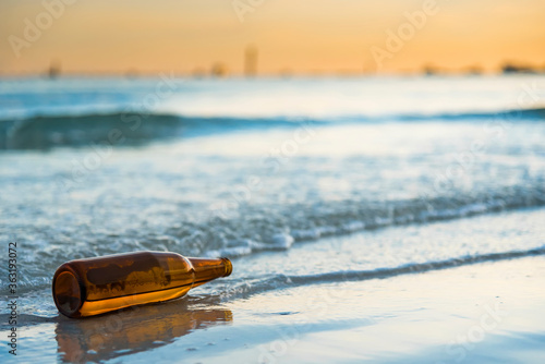 Brown glass bottle on Tawaen Beach in the dawn, the sun was rising, morning sunrise time on Koh Lan island.