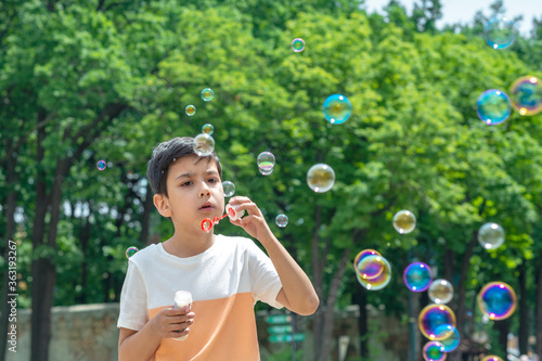 Shot of a young boy blowing bubbles in the park on vacation