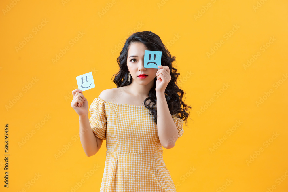Woman holding notes with painted emoticons, the concept of a good and bad day, mood, work Woman holding notes with painted emoticons, the concept of a good and bad day, mood, work