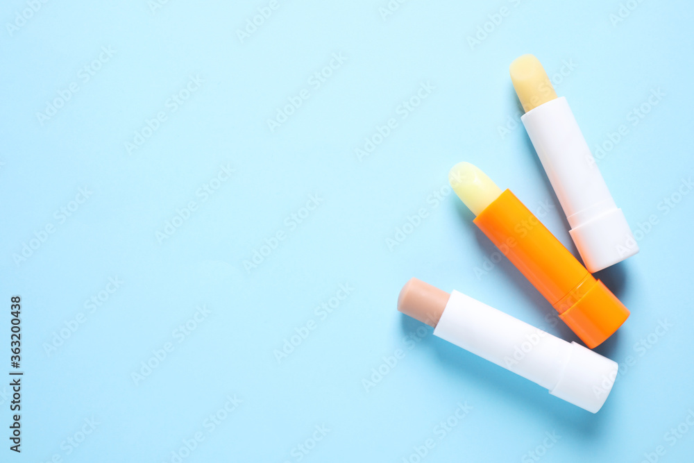 Hygienic lipsticks on light blue background, flat lay. Space for text Hygienic lipsticks on light blue background, flat lay. Space for text