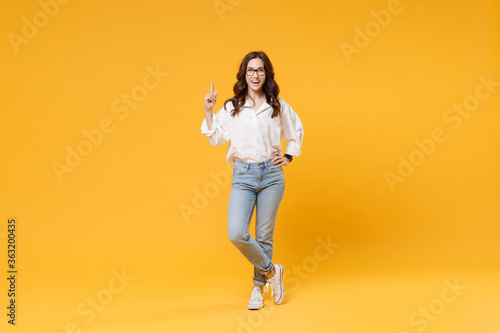 Excited young brunette business woman in white shirt glasses isolated on yellow background. Achievement career wealth business concept. Mock up copy space. Holding index finger up with great new idea. © ViDi Studio