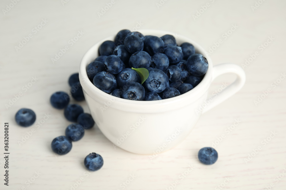 Fresh ripe blueberries in cup on white wooden table Fresh ripe blueberries in cup on white wooden table