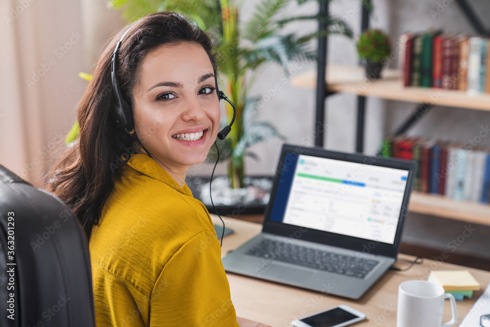 Portrait of beautiful freelancer female posing and working online with headset and looking at camera Portrait of beautiful freelancer female posing and working online with headset and looking at camera