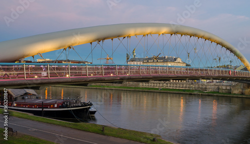 Father Bernatek Footbridge lit up at sunset with the Vistula River in Krakow, Poland