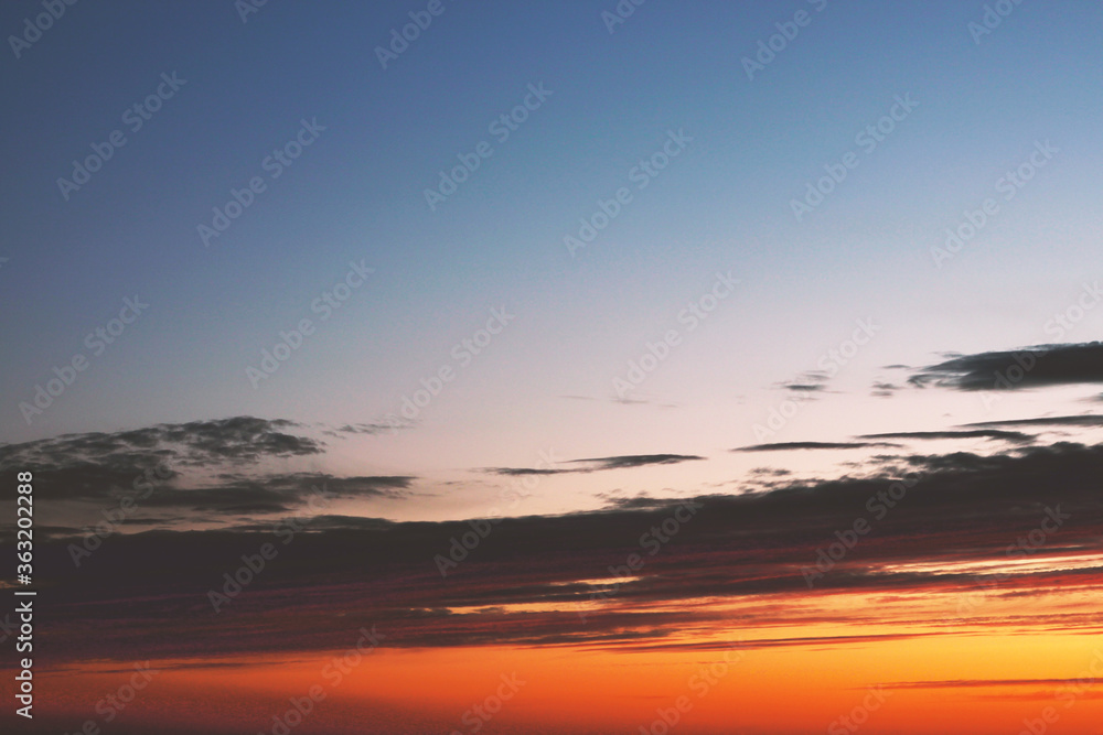 Bright orange sunset with dark clouds and blue sky Bright orange sunset with dark clouds and blue sky