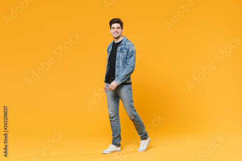 Smiling handsome young man guy wearing casual denim clothes posing isolated on yellow wall background studio portrait. People sincere emotions lifestyle concept. Mock up copy space. Looking camera.