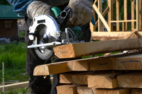 close-up of sawing a board with an electric circular saw.
