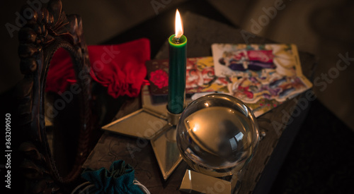 Magic crystal ball fortune teller ,love telling,  esoteric concept, mystical scene with candles, tarot cards on a table