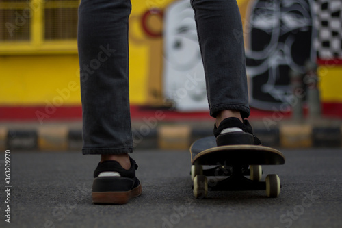 A young man standing while keeping one of his foot on a Skateboard. © Sausinbis