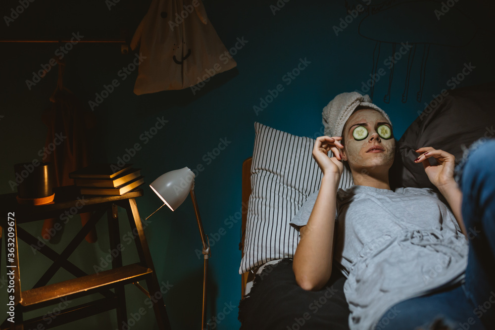 woman relaxing in her room. having applied cosmetic face mask