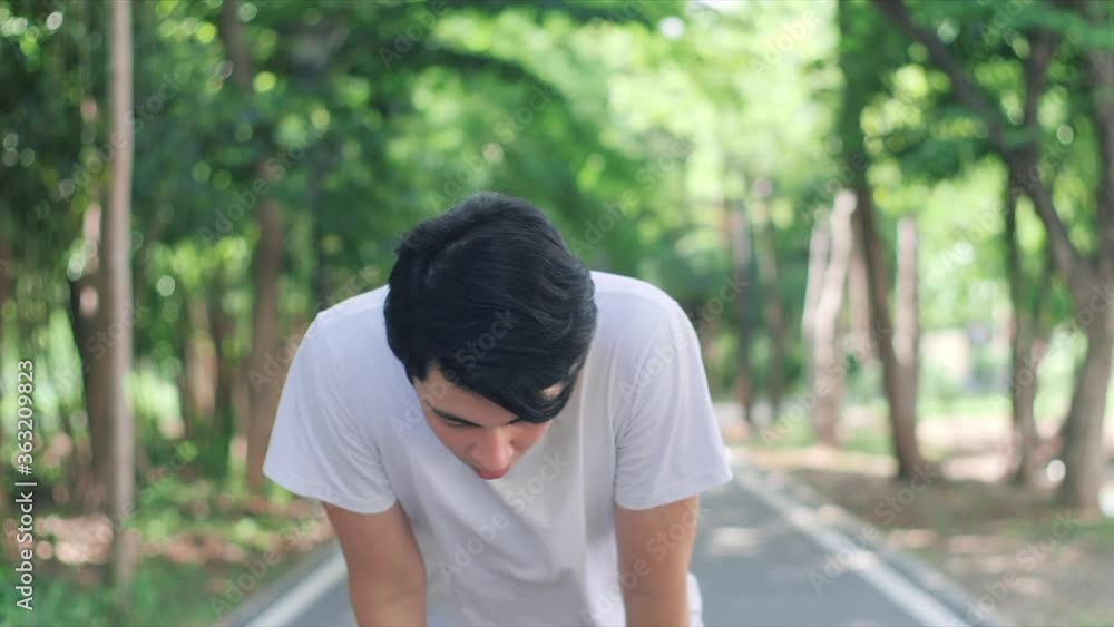Slow motion of sportive young Asian man finishing running and bending over to catch breath. Slow motion of sportive young Asian man finishing running and bending over to catch breath.