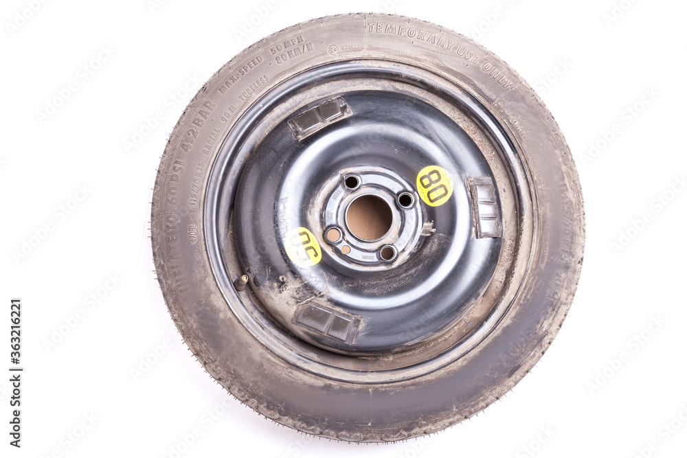 Full size spare tire of a black car isolated on white background in photo studio. Spare summer tire for sale or seasonal replacement in an auto parsing workshop. Full size spare tire of a black car isolated on white background in photo studio. Spare summer tire for sale or seasonal replacement in an auto parsing workshop.