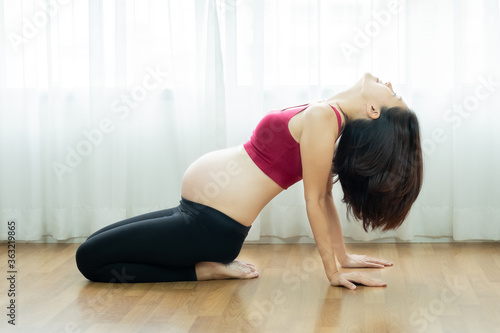 A beautiful asian young pregnant woman doing gymnastic exercise at home