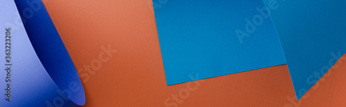 blue colorful paper on orange background, panoramic shot