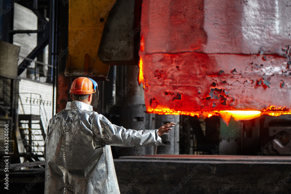 Worker blacksmith in protective clothing at the Forging shop