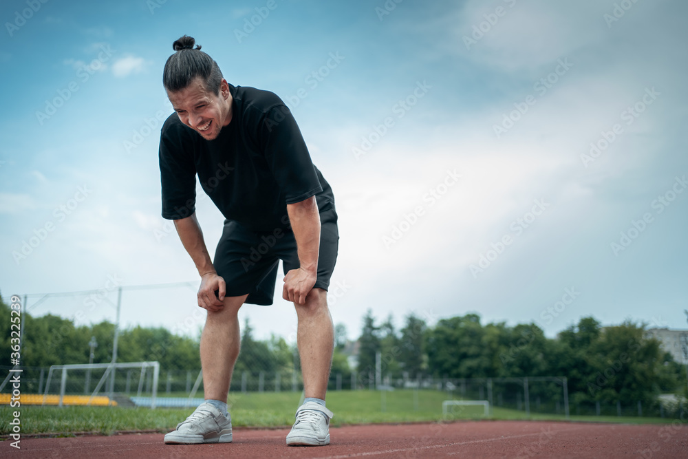 exhausted athlete resting on track after running or workout exercising outdoor