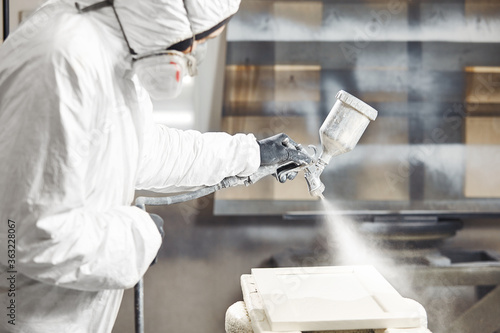 Man working with paint spray gun, airless spraying to wood