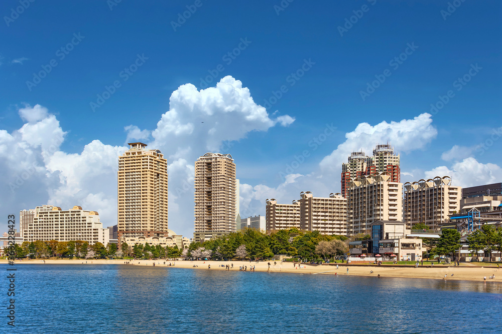 Seascape of artificial Odaiba island where tourists enjoying springtime along the Odaiba Marine Park and Odaiba beach with skyscrapers buildings in the background.