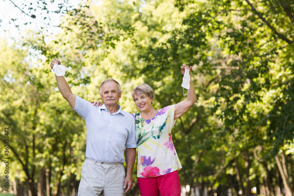 joyful elderly couple hold medical masks with hands up in the summer garden. end of a quarantine
joyful elderly couple hold medical masks with hands up in the summer garden. end of a quarantine