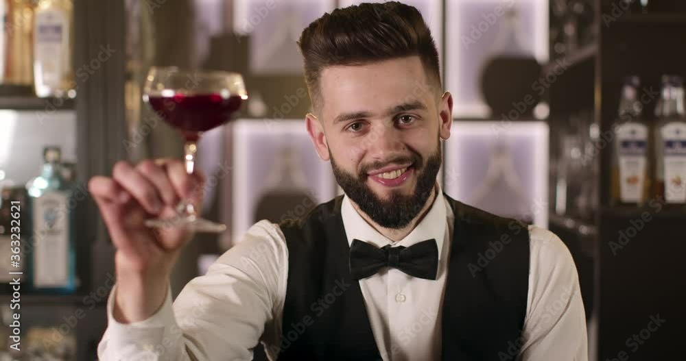 The bartender is raising his glass and looks at the camera. 4K The bartender is raising his glass and looks at the camera. 4K