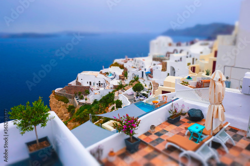 Famous greek iconic selfie spot tourist destination Oia village with traditional white houses and windmills in Santorini island, Greece. Toy camera tilt shift miniature effect