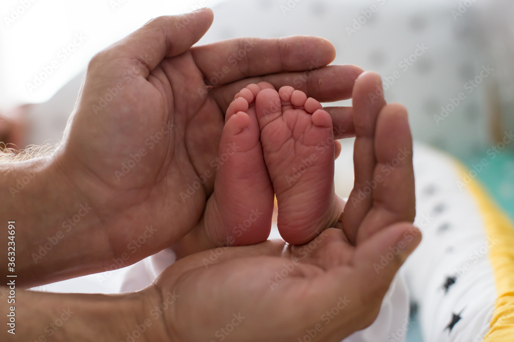 Baby feet in father hands. Tiny Newborn Baby's feet on female Shaped hands closeup. Happy Family concept. Beautiful conceptual image of Maternity