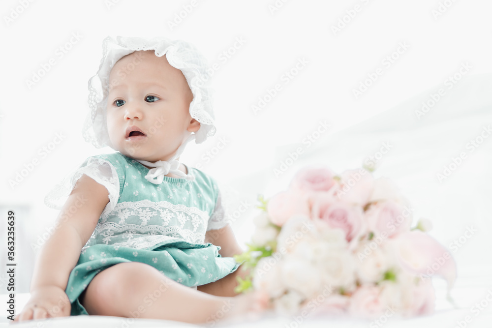 thai baby girl on white bed in bedroom relaxing and rose flower foreground thai baby girl on white bed in bedroom relaxing and rose flower foreground