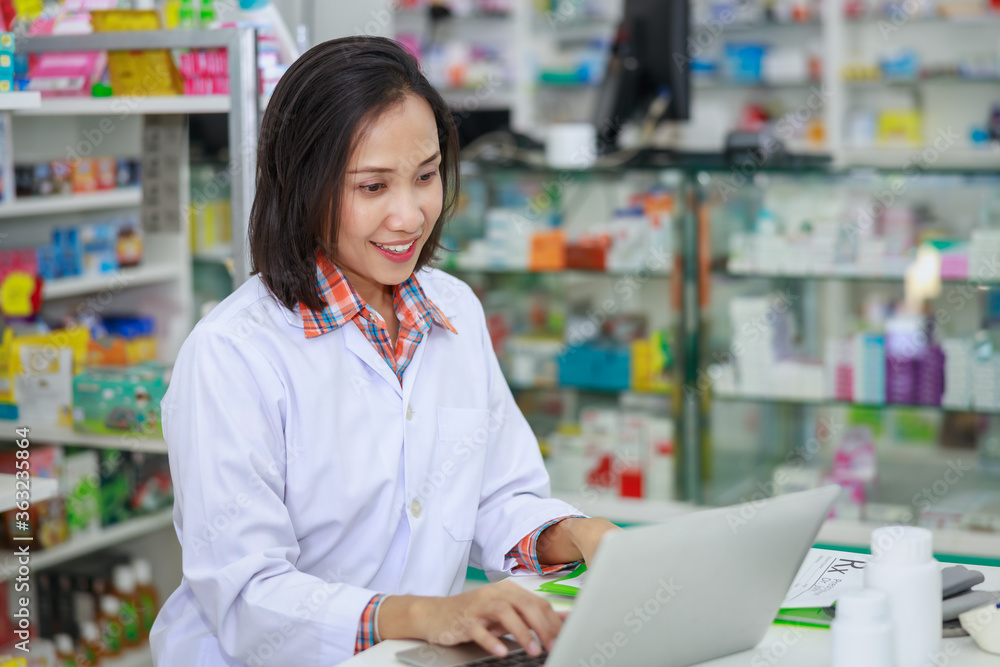 Asian Female doctor typing on her laptop computer in pharmacy store Thailand . Asian Female doctor typing on her laptop computer in pharmacy store Thailand .