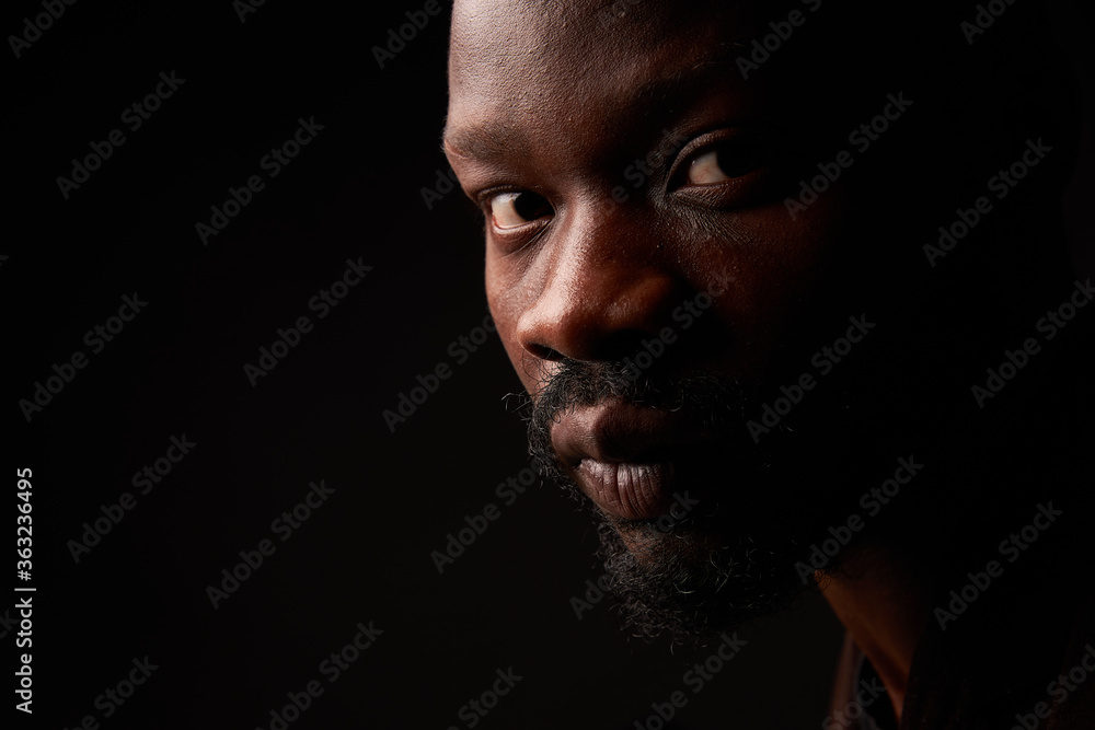 portrait photo of a dark-skinned handsome guy with a beard looking at the camera with serious face on a black background portrait photo of a dark-skinned handsome guy with a beard looking at the camera with serious face on a black background