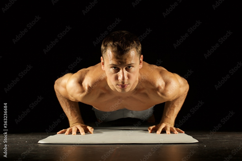 Young man doing push ups isolated on black background Young man doing push ups isolated on black background