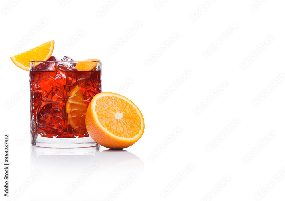 Negroni Cocktail in crystal glass with ice cubes and orange slices on white background with reflection. Negroni Cocktail in crystal glass with ice cubes and orange slices on white background with reflection.