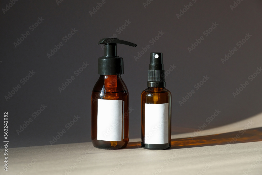 Amber glass cosmetic bottles mockups. Pump bottle with natural hand cream and spray bottle with body lotion. Cosmetic product packaging design