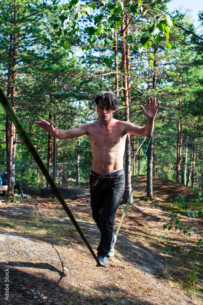 young man doing slackline rodeo in forrest outside sports activities, lifestyle people concept