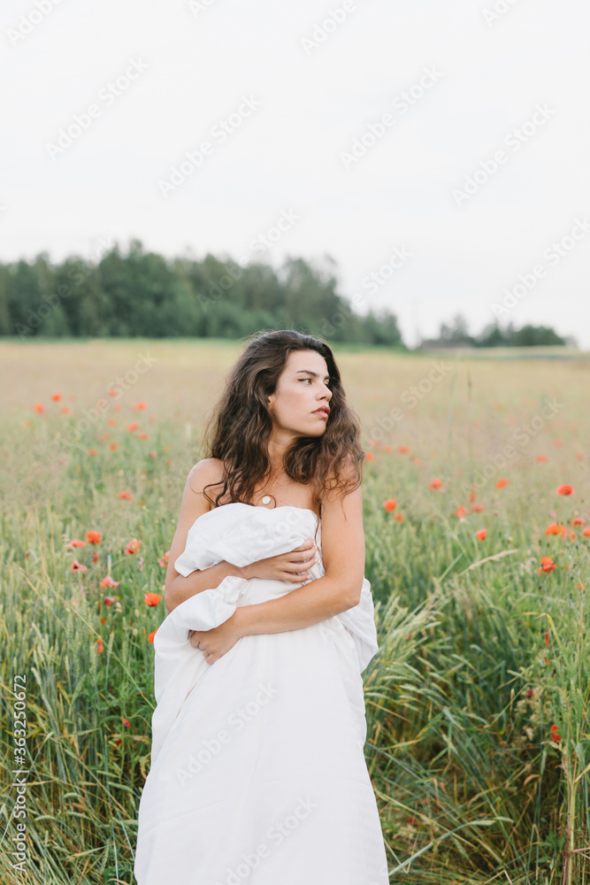 Girl wrapped in a blanket, with flowers. Stylish photo of a girl in a poppy field. Beautiful woman in a blanket in the field. Girl wrapped in a blanket, with flowers. Stylish photo of a girl in a poppy field. Beautiful woman in a blanket in the field.