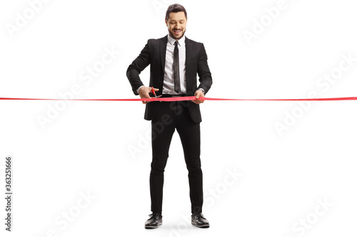 usinessman smiling and cutting a red ribbon tape with scissors