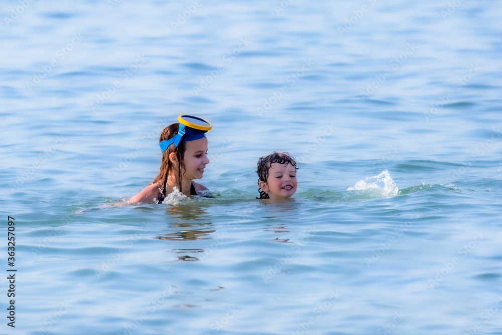 Brother and sister are swimming in the sea. Active summer vacation without gadgets. Travel destination