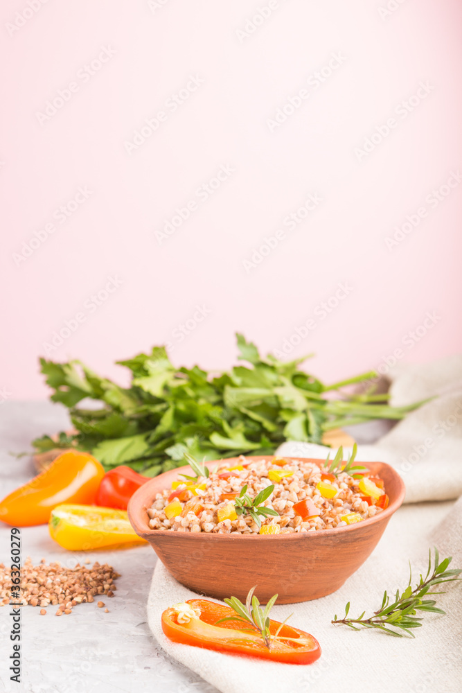 Buckwheat porridge with vegetables in clay bowl on a gray and pink background and linen textile. Side view, copy space, selective focus. Buckwheat porridge with vegetables in clay bowl on a gray and pink background and linen textile. Side view, copy space, selective focus.