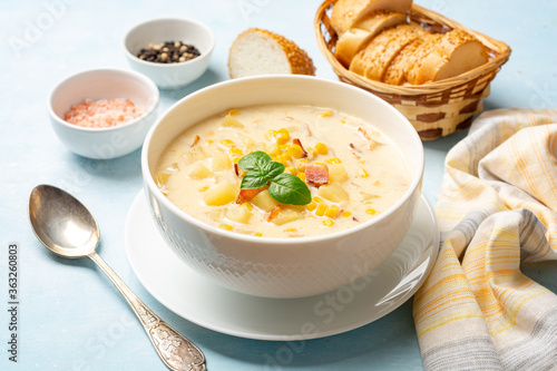 Corn chowder soup in white bowl on concrete background