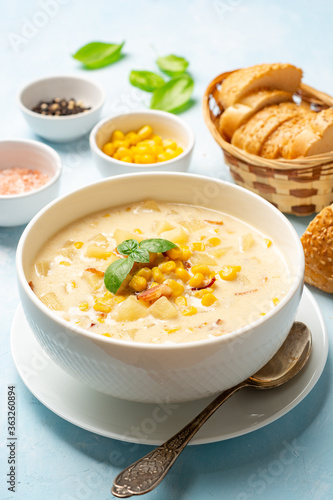 Corn chowder soup in white bowl on concrete background