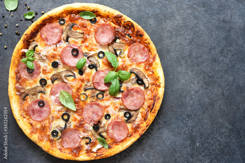 Pizza with salami, mushrooms and tomato sauce on a black background. View from above.