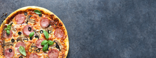 Pizza with salami, mushrooms and tomato sauce on a black background. View from above.