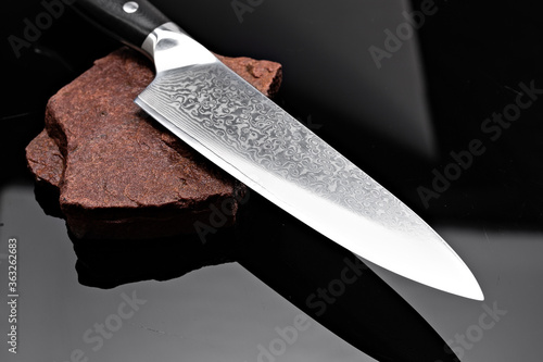Foto A large kitchen knife with a black handle on a dark background