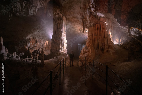 Young man standing between columns in Postojna Cave, Slovenia