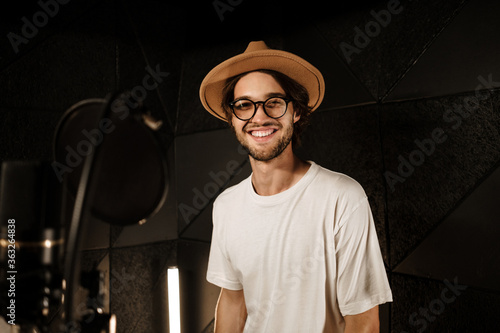 Handsome stylish male singer happily looking in camera recording song for new album in studio photo