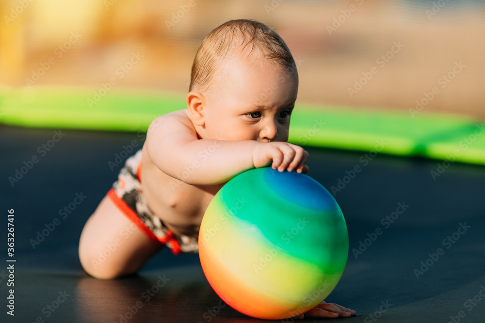 Little laughing kid playing with balls on the beach in the play area, summer vacation Little laughing kid playing with balls on the beach in the play area, summer vacation