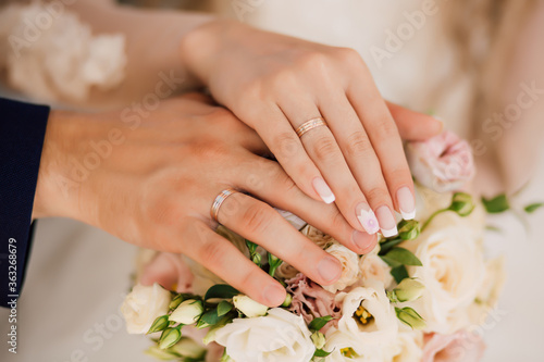 Wedding bride and groom rings on fingers on a bouquet