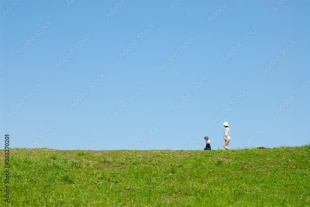 丘の上で遊ぶ親子（母親と子ども）