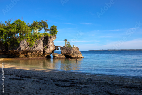 Tropical island landscape with still seashore, rocks and trees. Tropical vacation photo. Blue sea view. Hot day on seaside. Untouched island. Marine vacation banner template. South Asia travel